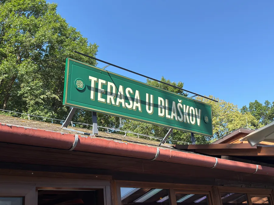 Zelená ceduľa s nápisom Terasa u Blaškov nad vstupom do baru na Počúvadle