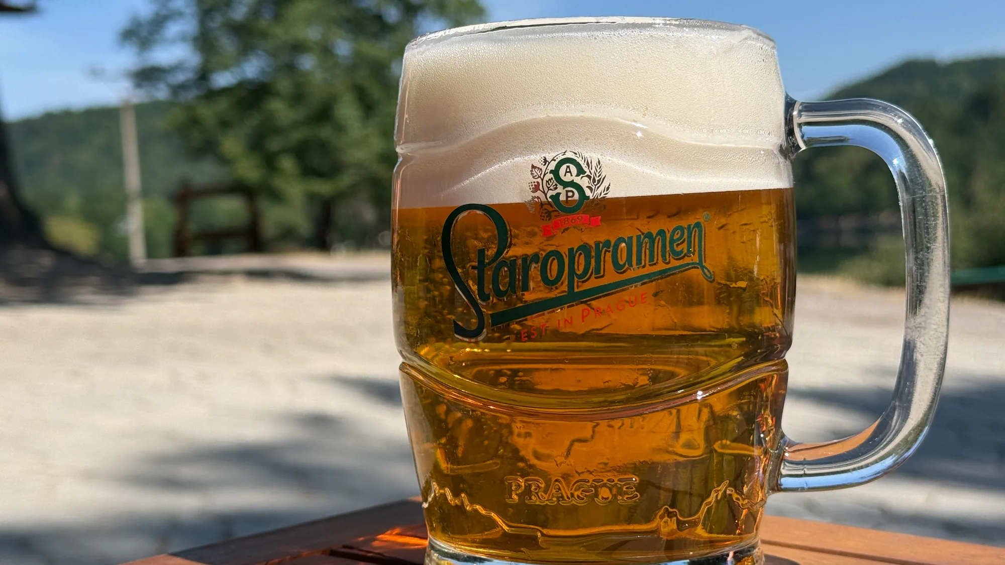 Bar u Blaškov na Počúvadle — pohár čapovaného piva Staropramen na drevenom stole letnej terasy